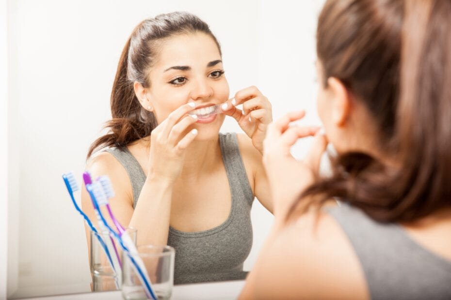 Woman using an over-the-counter teeth whitening strip at home