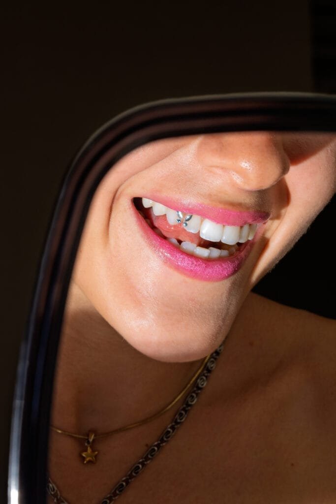 Woman showing off her new tooth gem in the mirror